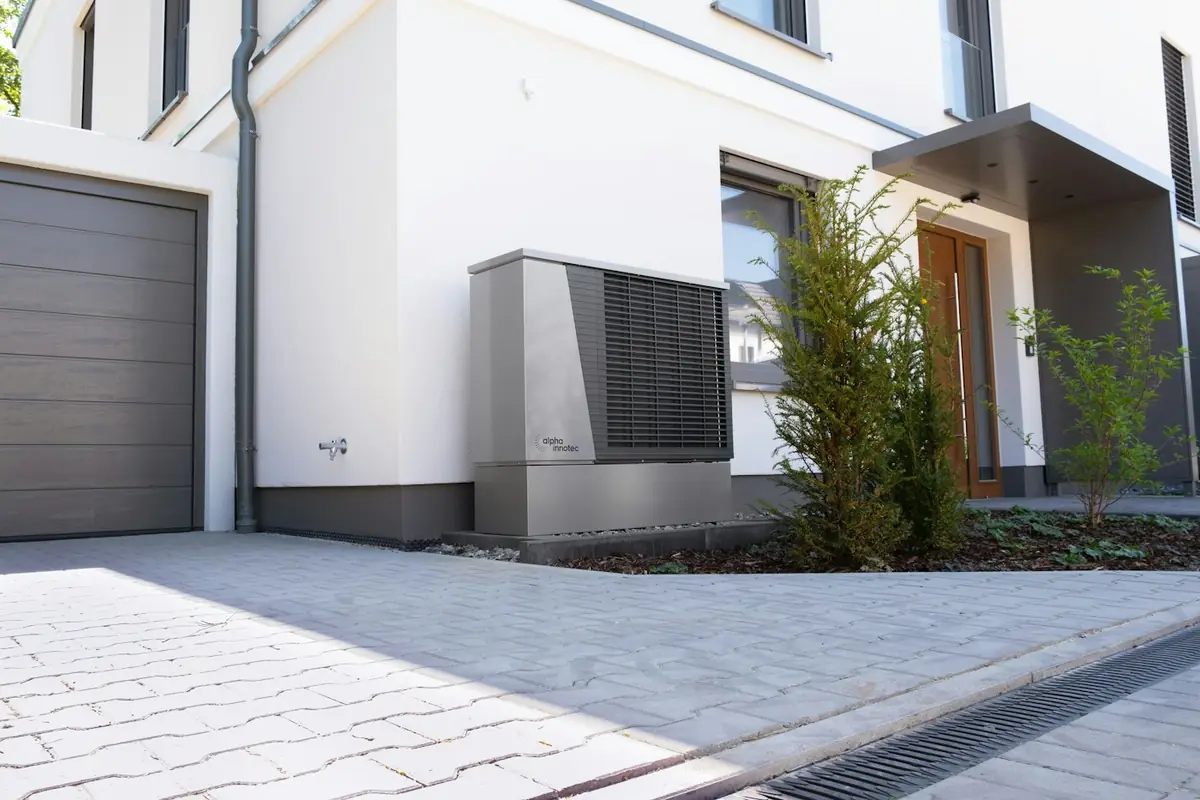 Outdoor heat pump unit installed beside the front of a house