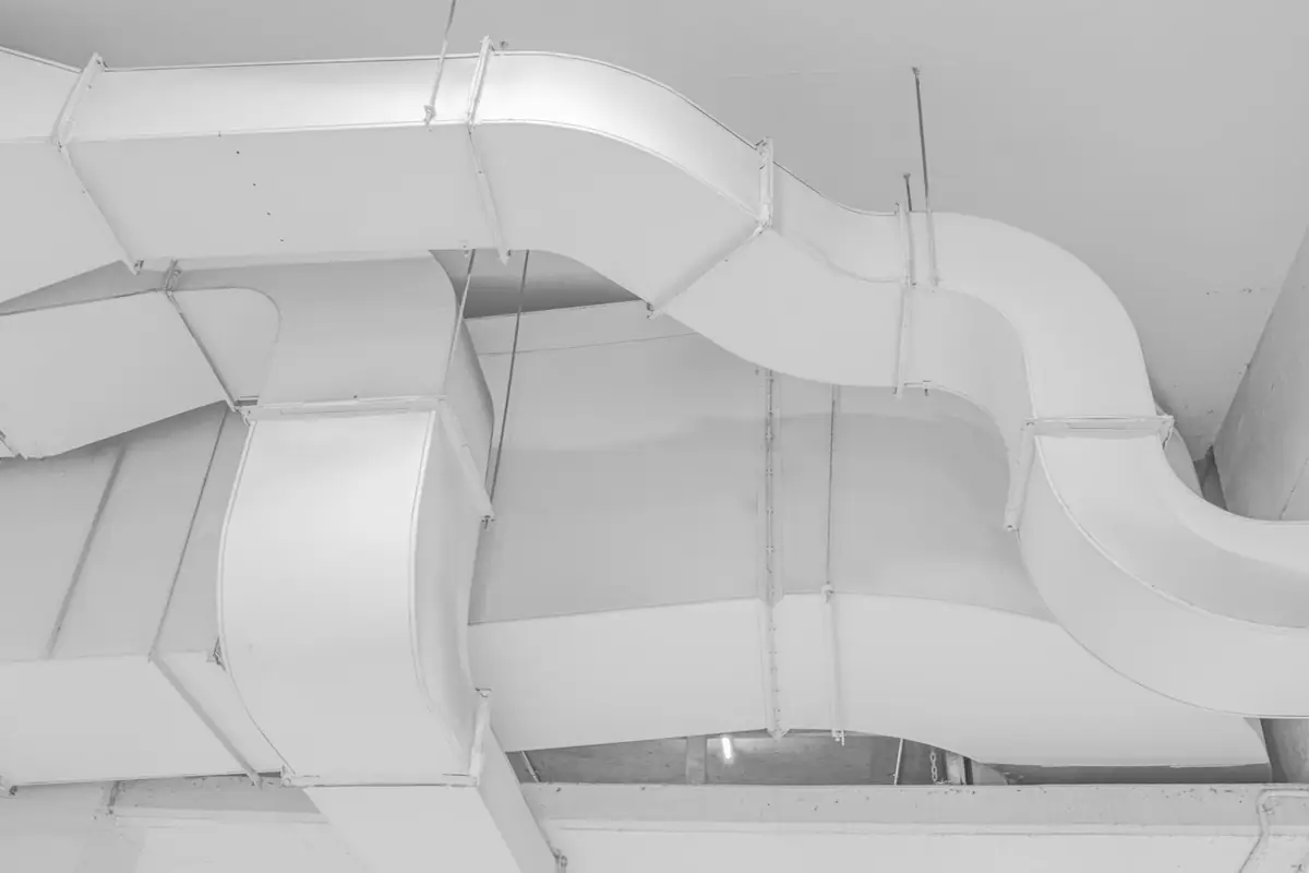 White sheet metal ductwork running along a ceiling